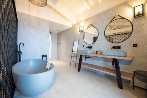 een badkamer met 2 wastafels en een groot bad bij L'Anderenis Boutique Hôtel in Andernos-les-Bains