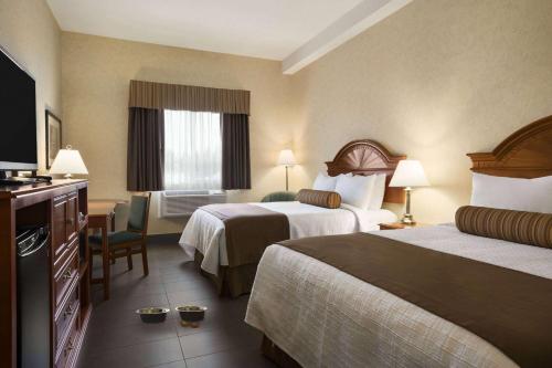 a hotel room with two beds and a television at Travelodge by Wyndham Strathmore in Strathmore