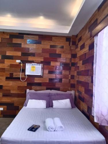 a bedroom with a bed with a wooden wall at Woodland Inn in El Nido