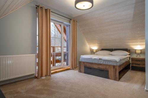 - une chambre avec un lit et une grande fenêtre dans l'établissement KARKONOSKIE CHATY, à Szklarska Poręba