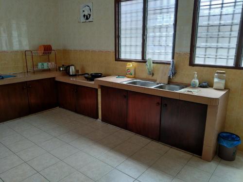 cocina con armarios de madera, fregadero y 2 ventanas en QQ Homestay en Ipoh
