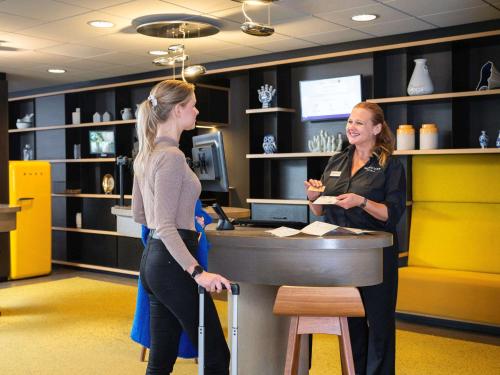 Mercure Amsterdam City Hotel في أمستردام: سيدتان واقفتان في مكتب في متجر