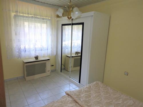 Schlafzimmer mit einem Bett, einem Waschbecken und einem Spiegel in der Unterkunft Ela`s Ferienoase Haus Ketsching in Görcsönydoboka