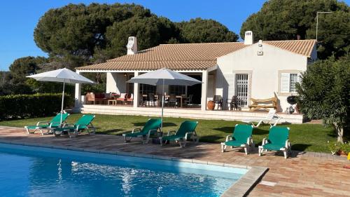 a house with chairs and umbrellas next to a swimming pool at Sol by Check-in Portugal in Vilamoura
