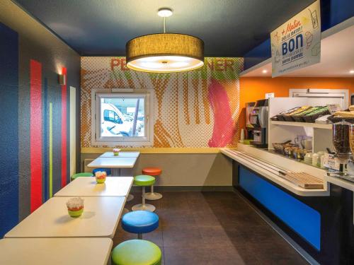 een fastfoodrestaurant met een bar en krukken bij ibis budget Cergy Pierrelaye in Pierrelaye