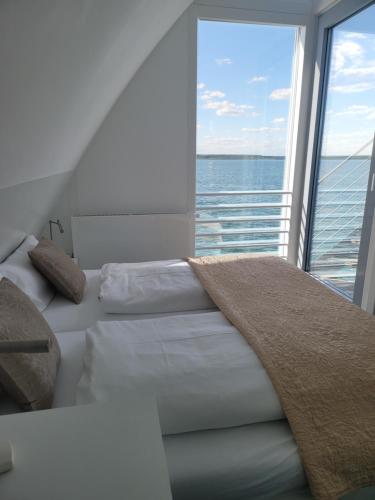 een slaapkamer met een bed en een groot raam bij schwimmendes Ferienhaus Sky in Elsterheide