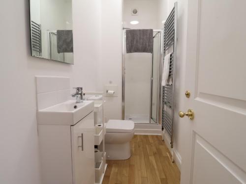 a white bathroom with a toilet and a sink at Feathers, Blythburgh in Halesworth