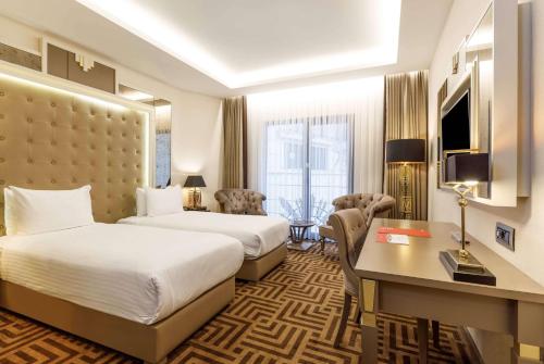 イスタンブールにあるRamada by Wyndham Istanbul Golden Hornのベッド2台とデスクが備わるホテルルームです。