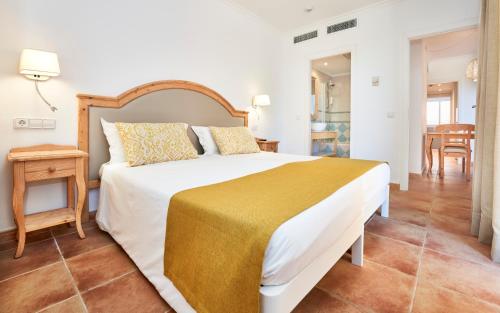 Un dormitorio con una cama grande y una mesa. en Insotel Cala Mandia Resort, en Cala Mendia