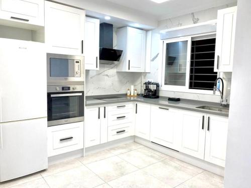 una cocina blanca con armarios y electrodomésticos blancos en Casa Mimi By Solymar Holiday, en Vélez-Málaga