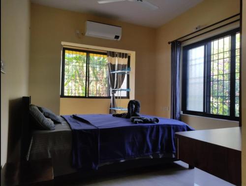 a bedroom with a bed with a blue blanket and two windows at SD D'Souza Heritage Moira Flats with Reserved Parking in Moira