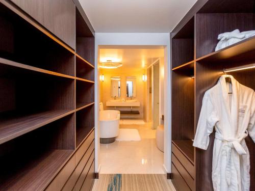 a walk in closet with a robe and a bathroom at Novotel Convention And Spa in Antananarivo