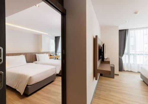 a hotel room with two beds and a television at Pure Eleven Hotel Bangkok in Makkasan