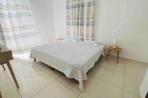 a white bed in a room with a window at VILLA FRUIT A PAIN T3 in Cayenne