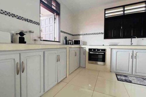 a large kitchen with white cabinets and a window at VILLA FRUIT A PAIN T3 in Cayenne