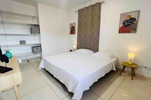 Un dormitorio blanco con una cama grande y una mesa en VILLA FRUIT A PAIN T3, en Cayenne