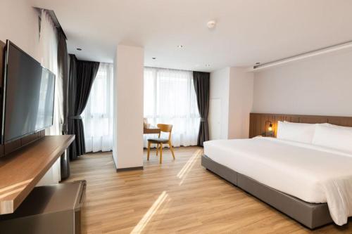 una camera d'albergo con un grande letto e una TV di Pure Eleven Hotel Bangkok a Makkasan