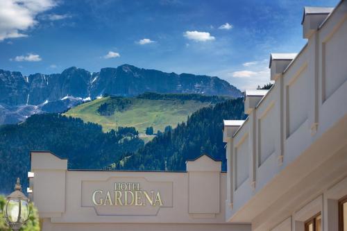 una señal para la caravana del hotel con montañas en el fondo en Gardena Grödnerhof - Hotel & Spa, en Ortisei