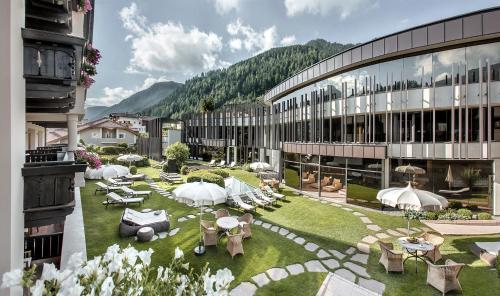 a building with a courtyard with tables and umbrellas at Gardena Grödnerhof - Hotel & Spa in Ortisei