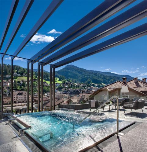 a hot tub with a view of the mountains at Gardena Grödnerhof - Hotel & Spa in Ortisei