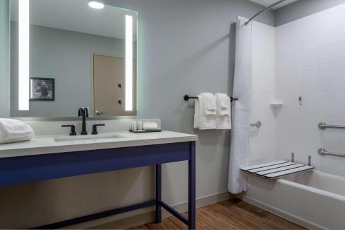 een badkamer met een wastafel, een bad en een spiegel bij AmericInn by Wyndham San Angelo in San Angelo