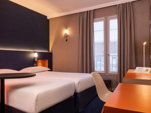 Cette chambre comprend 2 lits et une table. dans l'établissement ibis Styles Bourg La Reine, à Bourg-la-Reine
