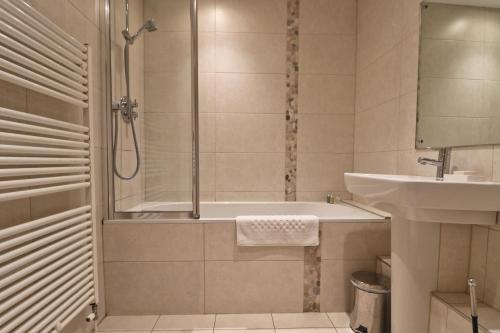 a bathroom with a shower and a sink and a tub at APARTMENT BY THE BEACH, courtyard garden in St Merryn