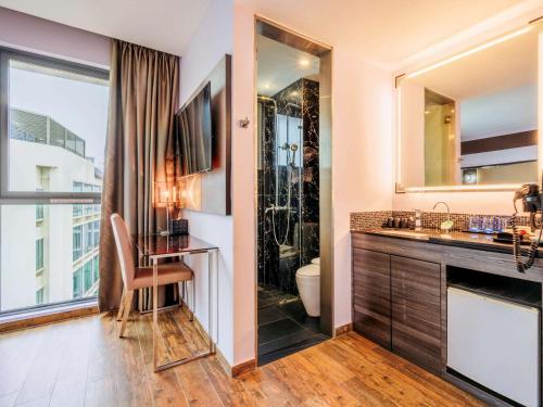 a bathroom with a sink and a toilet and a mirror at Mercure Singapore Tyrwhitt in Singapore