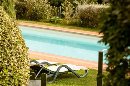 two lawn chairs sitting next to a swimming pool at Casetta di Butia, Glicine Apartment in Borgo a Mozzano