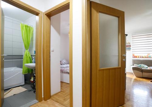 ein Bad mit einer Tür, die sich zu einem Badezimmer mit einem Waschbecken öffnet in der Unterkunft Apartman Teo in Lukavica