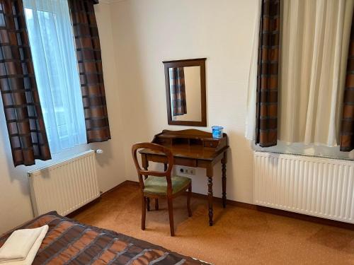 - une chambre dotée d'un bureau avec un miroir et une chaise dans l'établissement Bernadett Villa Apartman 3, à Bük