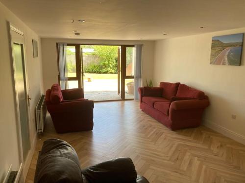 a living room with two red couches and a wooden floor at RedBayBeach-House in Glenariff