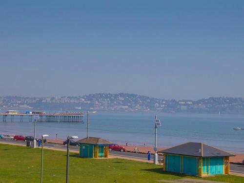 a beach with two buildings and a pier in the water at The Briars - Adults Only in Paignton