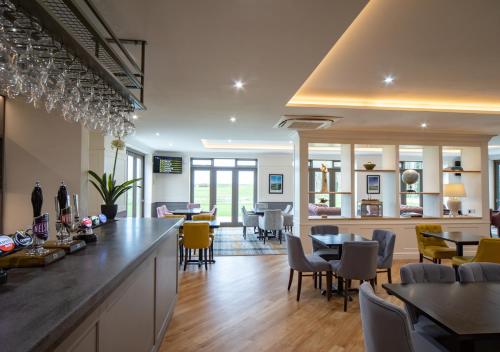 a dining room with a bar and tables and chairs at Heacham Manor Hotel in Hunstanton