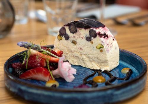 a piece of cake on a blue plate with fruit at Heacham Manor Hotel in Hunstanton