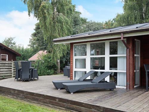 une terrasse en bois avec des chaises et une maison dans l'établissement 10 person holiday home in Juelsminde, à Juelsminde