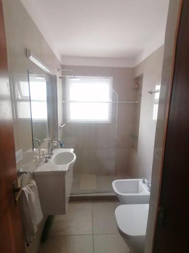 baño con lavabo y aseo y ventana en Playa Grande 2 ambientes en Mar del Plata