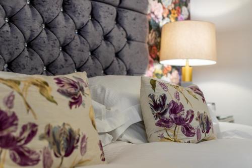 a bedroom with a bed with pillows and a lamp at Holly Lodge Guest House with FREE off site health club in Windermere