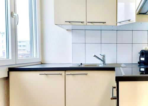 a white kitchen with a sink and a window at El Hamra - cozy - by PA in Luzern