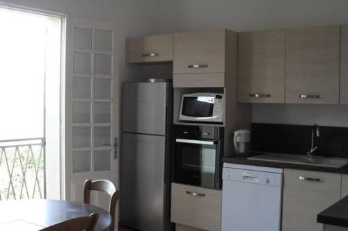 La cuisine est équipée d'un réfrigérateur, d'un four micro-ondes et d'une table. dans l'établissement Appartement 8 pers. - Domaine de Padulone ALERIA, à Aléria