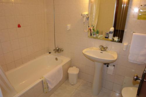 een badkamer met een wastafel, een bad en een wastafel bij Hotel Sirius in Funchal