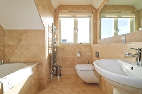 a bathroom with a sink and a tub and a toilet at Contemporary beachside apartment in St Merryn