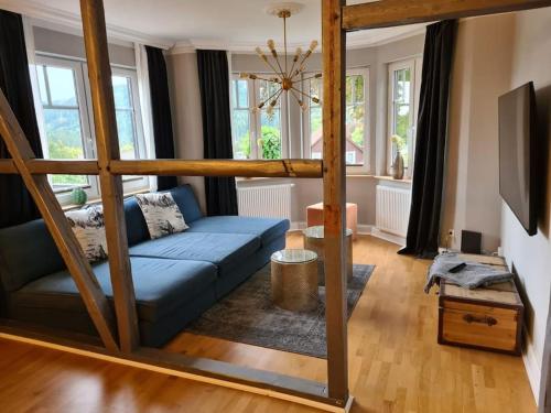 een woonkamer met een blauwe bank en een aantal ramen bij Gruppenhaus mit Grillkota für 16 Personen in Hahnenklee in Hahnenklee-Bockswiese