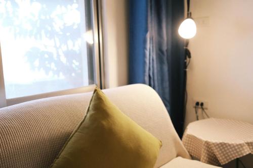 a yellow pillow sitting on a couch next to a window at Jiufen Breeze 九份惠風民宿ｌ6人包棟小屋 in Jiufen