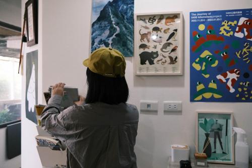 a woman is looking at a painting on a wall at Jiufen Breeze 九份惠風民宿ｌ6人包棟小屋 in Jiufen