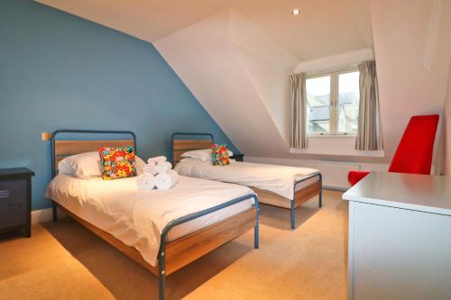 two beds in a room with blue walls at STYLISH, BEACHSIDE apartment, sea views in St Merryn