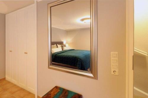 einen Spiegel an der Wand mit einem Bett in einem Zimmer in der Unterkunft Strandhaus 4,  App. Strandresidenz in Westerland