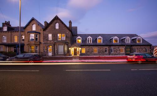 uma grande casa de tijolos com carros estacionados em frente em Dalesgate Hotel - Self Check In em Keighley