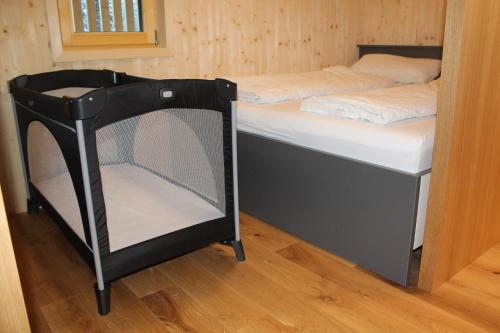 Apartment Bergblick-Mellau في ميلاو: سرير صغير في غرفة مع أرضية خشبية