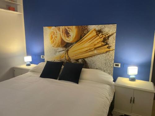 a bedroom with a white bed with a painting on the wall at MalaMù BnB Eventi in Rigosa